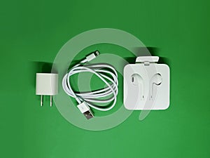 IPhone Power Adapter, Lightning Cable and EarPods on the green background