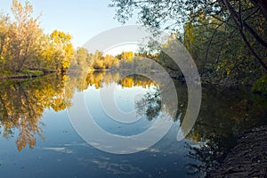 October forest reflected in the calm waters of a lake makes a mirror effect
