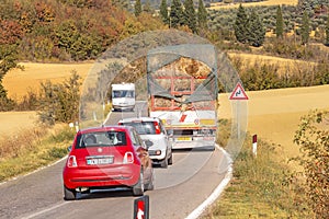 Car overtakes truck loaded with hay stacks in countryside road. Dangreous accident and
