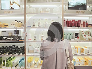 Young Asian woman standing in front of a shelf with skincare products