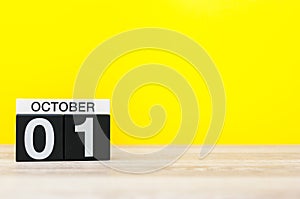 October 1st. Day 1 of month, wooden color calendar on yellow background. Autumn time. Empty space for text photo