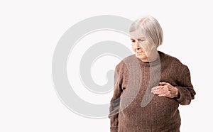 Octogenarian old lady complains of pain in her heart. She keeps her hand on her chest in the heart area.