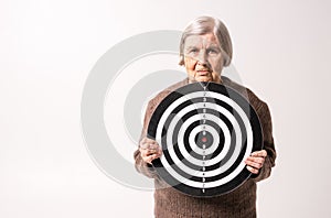 Octogenarian old lady holding target in her wrinkled hands