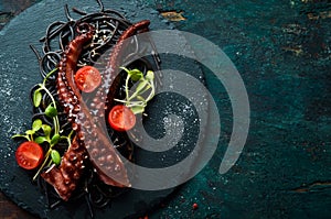 Octopus tentacles baked in garlic sauce and black pasta with cuttlefish ink. Luxury restaurant food. Seafood.