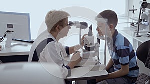 Oculist check eyesight of little boy with modern equipment