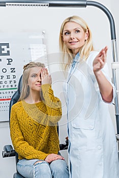 oculist gesturing while examining attractive patient