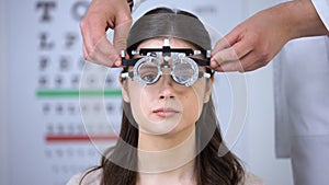 Oculist putting optical trial frame on girl sight correction diopter measurement