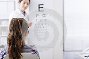 Oculist testing a young patient`s eyesight using an eye chart