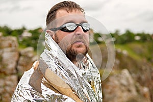An oddball in glasses with an axe in his hand and dressed in foil against the sky