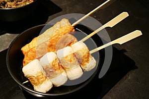 Oden, processed fishcakes stewed in a light, soy-flavored dashi broth, serving on black bowl. Japanese traditional food