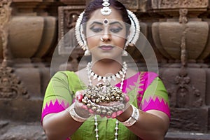 An odissi artist wears traditional costume holding ghungroo in hand