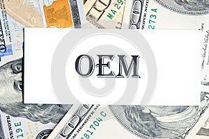 OEM original equipment manufacturer concept. Text on a white business card against the background of money, a business concept