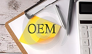 OEM word on a yellow sticky with calculator, pen and clipboard