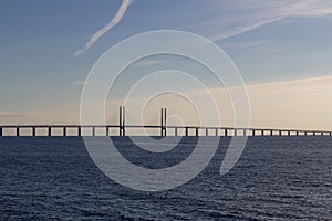 The Oeresund bridge with dark blue water and a bright blue sky during sunset with soft clouds