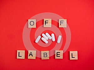 Off label approved medicine pill use. Covid-19 therapy. Words off label and white capsules or pill drugs on colored red paper