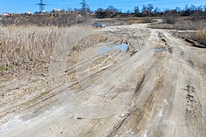 Off-piste. Deep rubber tracks on the road is covered with wet dirty sand, off-road. Traces of tires in the dirt. Impassable road