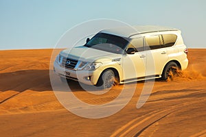 Off-road adventure with SUV in Arabian Desert at sunset. Offroad vehicle bashing through sand dunes in Dubai desert