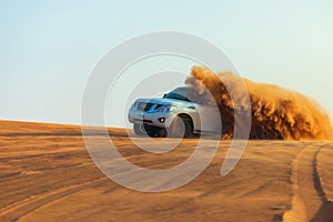 Off-road adventure with SUV in Arabian Desert at sunset. Offroad vehicle bashing through sand dunes in Dubai desert