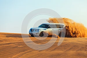 Off-road adventure with SUV in Arabian Desert at sunset. Offroad vehicle bashing through sand dunes in Dubai desert.