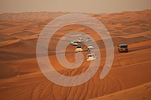 Off-road adventure with SUV driving in Arabian Desert at sunset. Offroad vehicle bashing through sand dunes in Dubai desert.