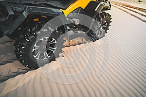 Off-road ATV wheel close up. Tourist on the Quad bike rides through the sandy desert. Extreme fun in the desert of MUI ne. Vietnam