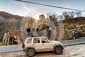 Off road car by abandoned burnt village