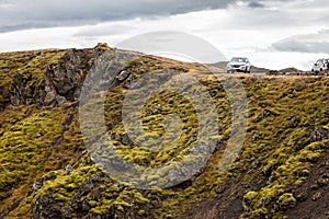 Off-road car parked at the volcanic cliff in Gjain canyon, ÃžjÃ³rsÃ¡rdalur valley, South Iceland