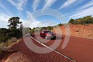 Off road car on red tarmac in high mountains