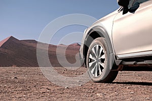 Off-road car stands in the red sands of the Namib Desert on a sunny day. Sossusvlei, Namibia. Africa