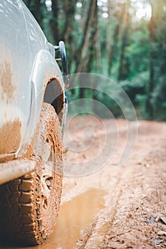 Off road cars on muddy road. Low angle view of front of SUV on mountain road