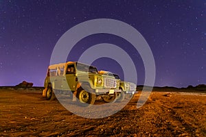 Off-road cars under starlight sky night desert landscape at Hegra, Al Ula, Saudi Arabia