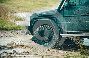 Off-road Jeep car on bad gravel road. Mud and water splash in offroad racing. Off-road travel on mountain road.