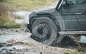 Off-road Jeep car on bad gravel road. Mud and water splash in offroad racing. Off-road travel on mountain road.