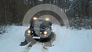 Off-road. Jeeping. SUV 6x6 overcomes a large puddle on a dirt road in the winter forest