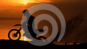 Off-road motorbike extreme cornering. Motorcyclist at sunset near the river. Extreme motocross bike, dirt from under the