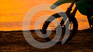 Off-road motorbike extreme cornering. Motorcyclist at sunset near the river. Extreme motocross bike, dirt from under the