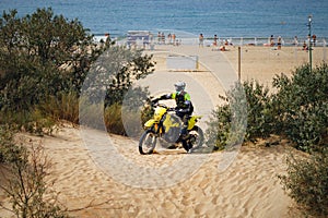 off-road motorcycle enduro motocross rider on sand dune, sea beach background