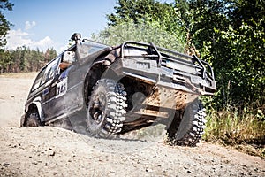 Off road racing car driving along the dusty road