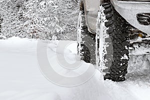 Off-road suv car wheel on snow in snowdrift, background of winter woods nature. Extreme winter, sports, travel, driving