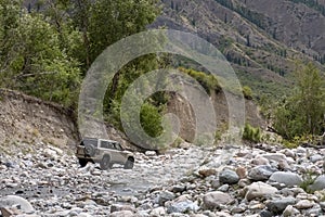 Off road suv moving on rocky bottom of dried river. Outdoor landscape. Adventure travel. Off road trail concept. Offroad car.