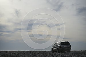 Off Road SUV, sport utility vehicle, MOTOR on Black sea coast, beach. car against backdrop top of mountains, blue sky. BATUMI,