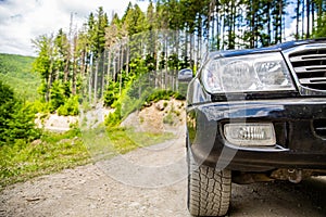 Off-road travel on mountain road. Travel concept with big car . Closeup photo of offroad wheel. Closeup of car wheel on