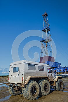 Off-road vehicle on the background of the oil rig.