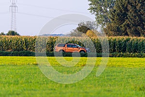 An off-road  vehicle drives through the fields and behind the vehicle is a cornfield