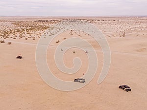 Off-road vehicle driving along a desert terrain with mountains in the background