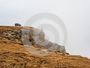 Off-road vehicle on the edge of a autumn steep cliff with dense