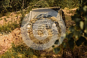 Off-road vehicle goes on the mountain. Mudding is off-roading through an area of wet mud or clay. Tracks on a muddy photo