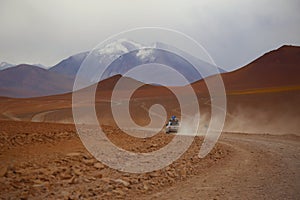 An off road vehicle running in the dusty of desert. Adventure in Bolivia highlands in the Andes.