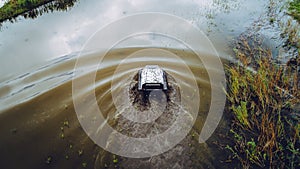 An off-road vehicle sails on the river. aerial above view top