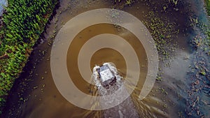 An off-road vehicle sails on the river. aerial above view top